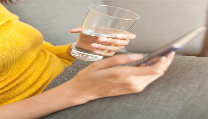 摄图网_323724219_拿着一杯水 使用智能手机的漂亮女人 (b) 利用智能电话(企业商用).jpg